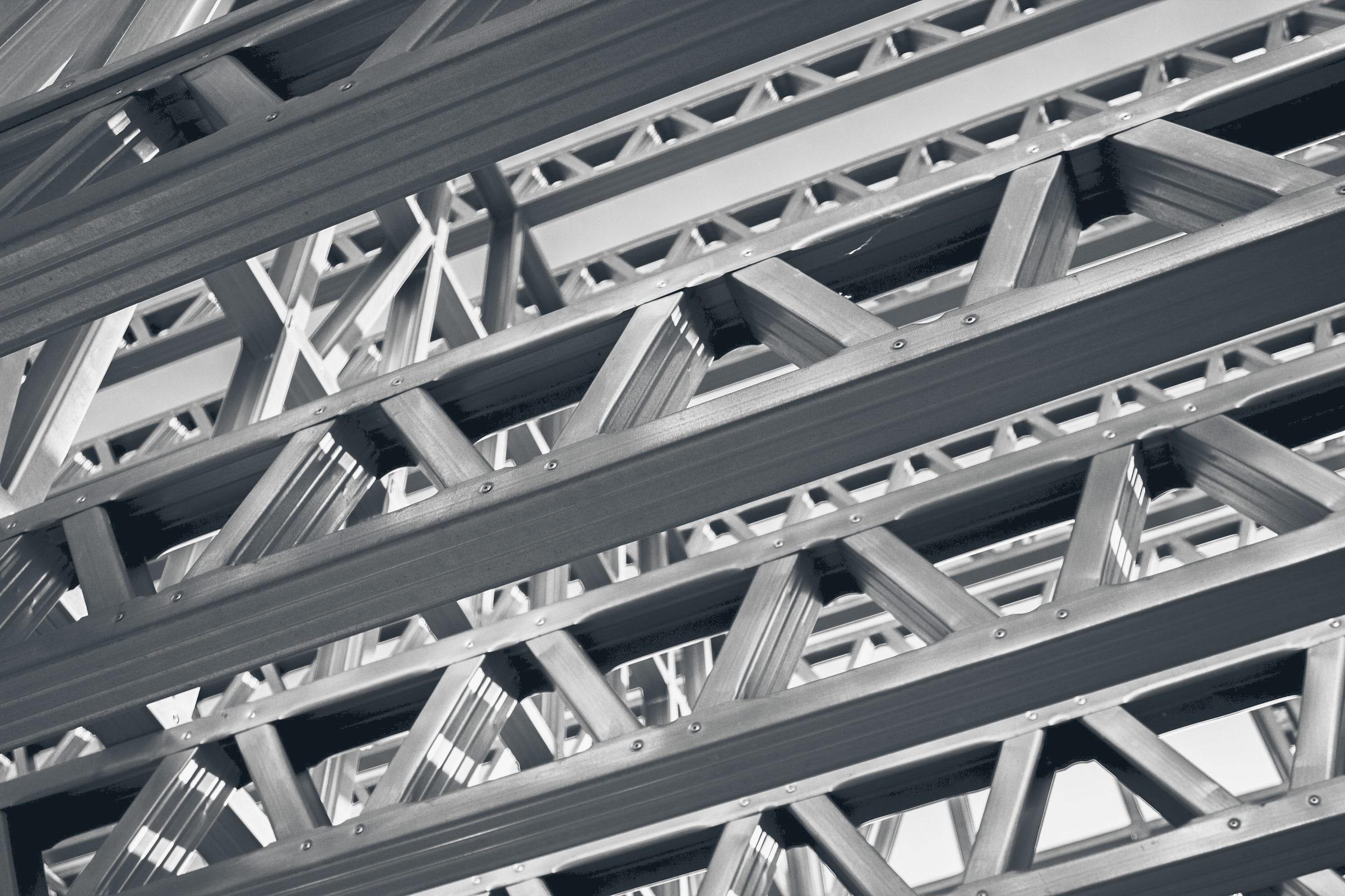 Close-up of screwed light-gauge steel trusses seen from below.
