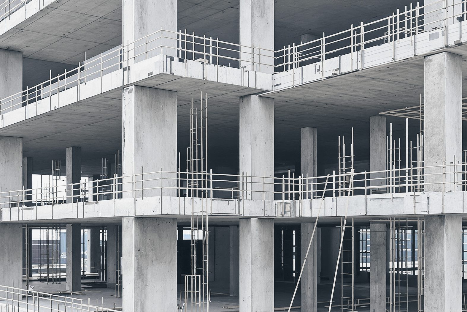 Cast-in-place concrete columns and slab edges of a building under construction, lined with temporary guardrails.