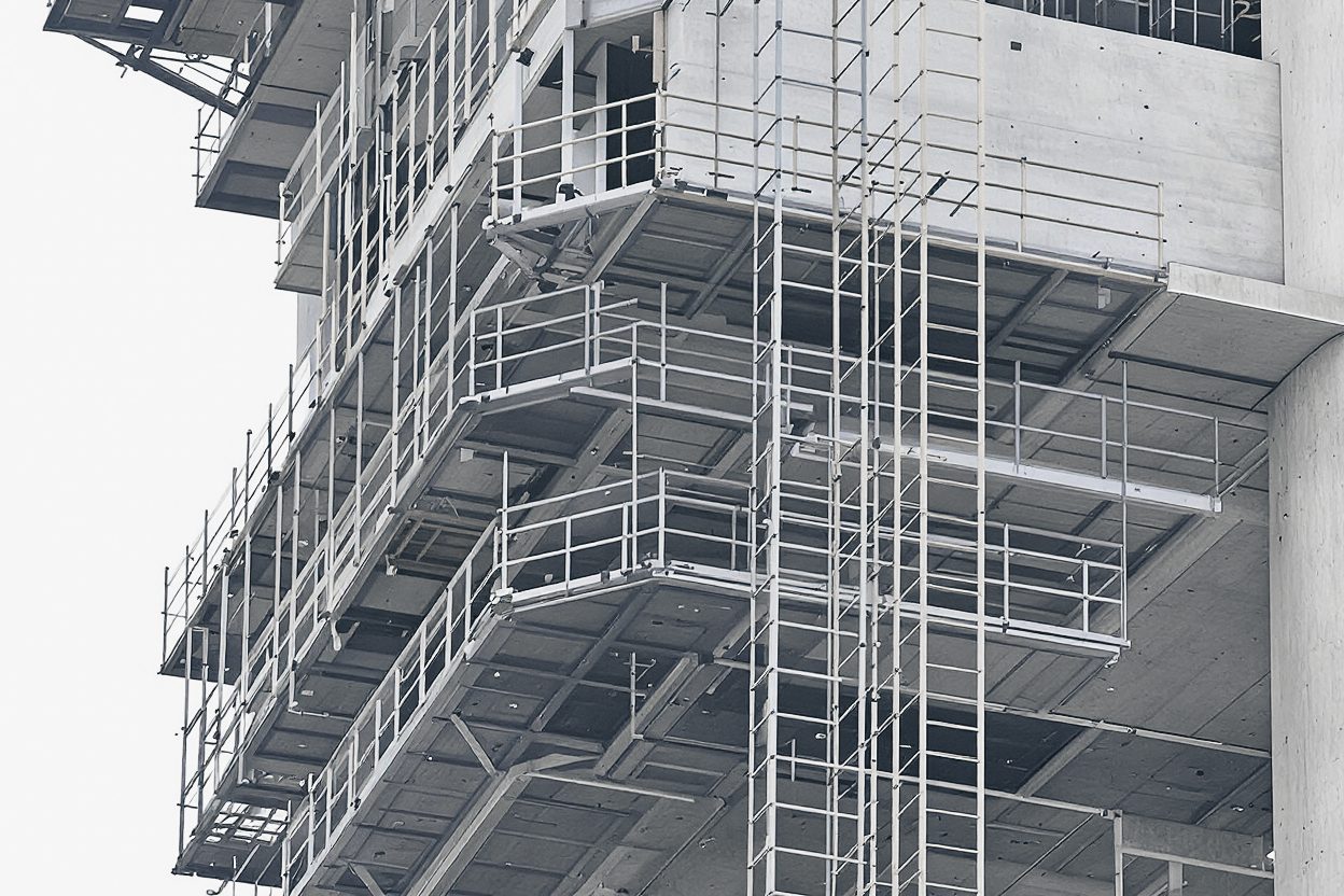 Climbing-form work platforms with guardrails on the concrete core of a tower under construction.