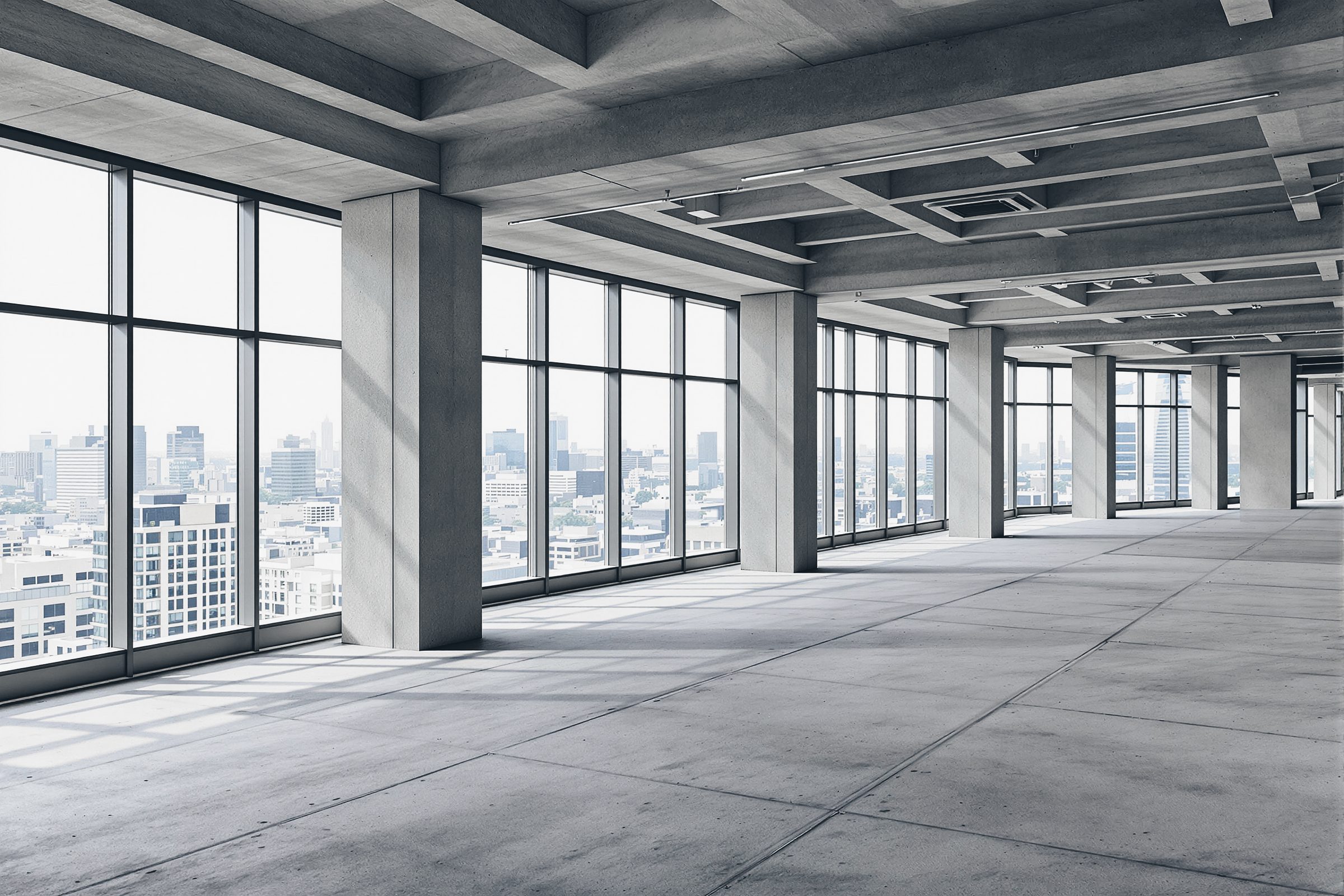 An empty office floor before fit-out: concrete columns, exposed concrete ceiling and full-height glazing over a hazy city.